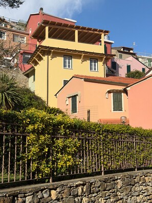 A multi-story building with balconies, a stone wall, and a metal fence. - Apartment 'Timo' with Sea View, Wi-Fi and Air Conditioning (Moglio)