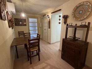 A dining area with a wooden table and chairs, a hanging light fixture, a decorative plate, and a cabinet with drawers. - Apartment 'Timo' with Sea View, Wi-Fi and Air Conditioning (Moglio)