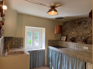 A kitchen with a stone wall, a window, a sink, and a ceiling fan. - Apartment 'Timo' with Sea View, Wi-Fi and Air Conditioning (Moglio)