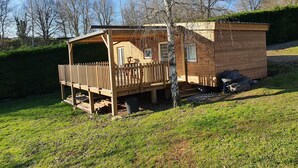 A wooden cabin with a deck and a small attached shed.