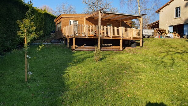 A wooden deck with a wooden fence, a grassy yard, and a building with a garage.