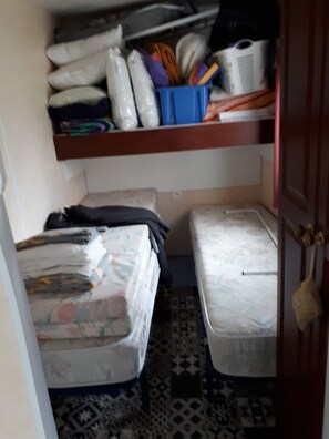 A compact room with two beds, a shelf with various items, and a patterned floor. - Chalet at the Gateway to the Green Venice (Saint-Hilaire-des-Loges)