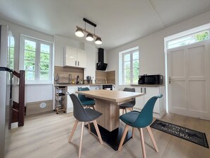 Une cuisine moderne dotée d’un îlot central, de meubles blancs et d’un coin repas avec des chaises de couleur turquoise.