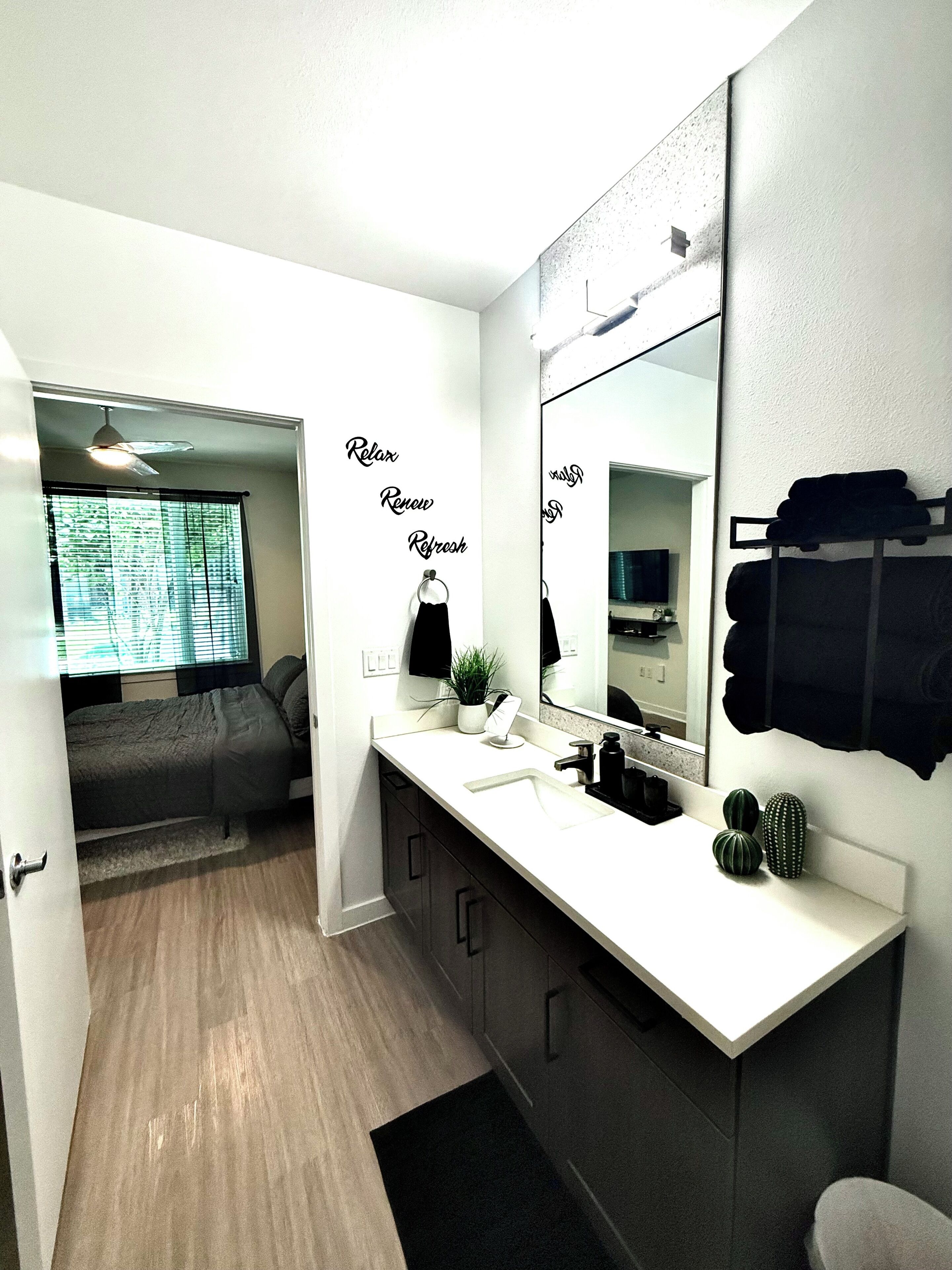 Une salle de bain moderne avec un grand miroir, un lavabo et un espace douche.