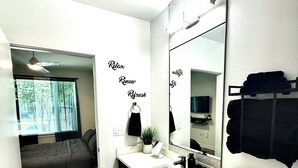 Et moderne badeværelse med et stort spejl, en vask og et bruseområde.