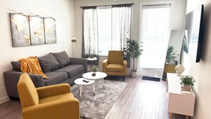 En stue med sofa, to lænestole, et sofabord, et lille sidebord, en globus og en plante.