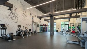 Ein Fitnessstudio mit Cardiogeräten, Gewichten und einer Wand mit abstrakter Kunst.