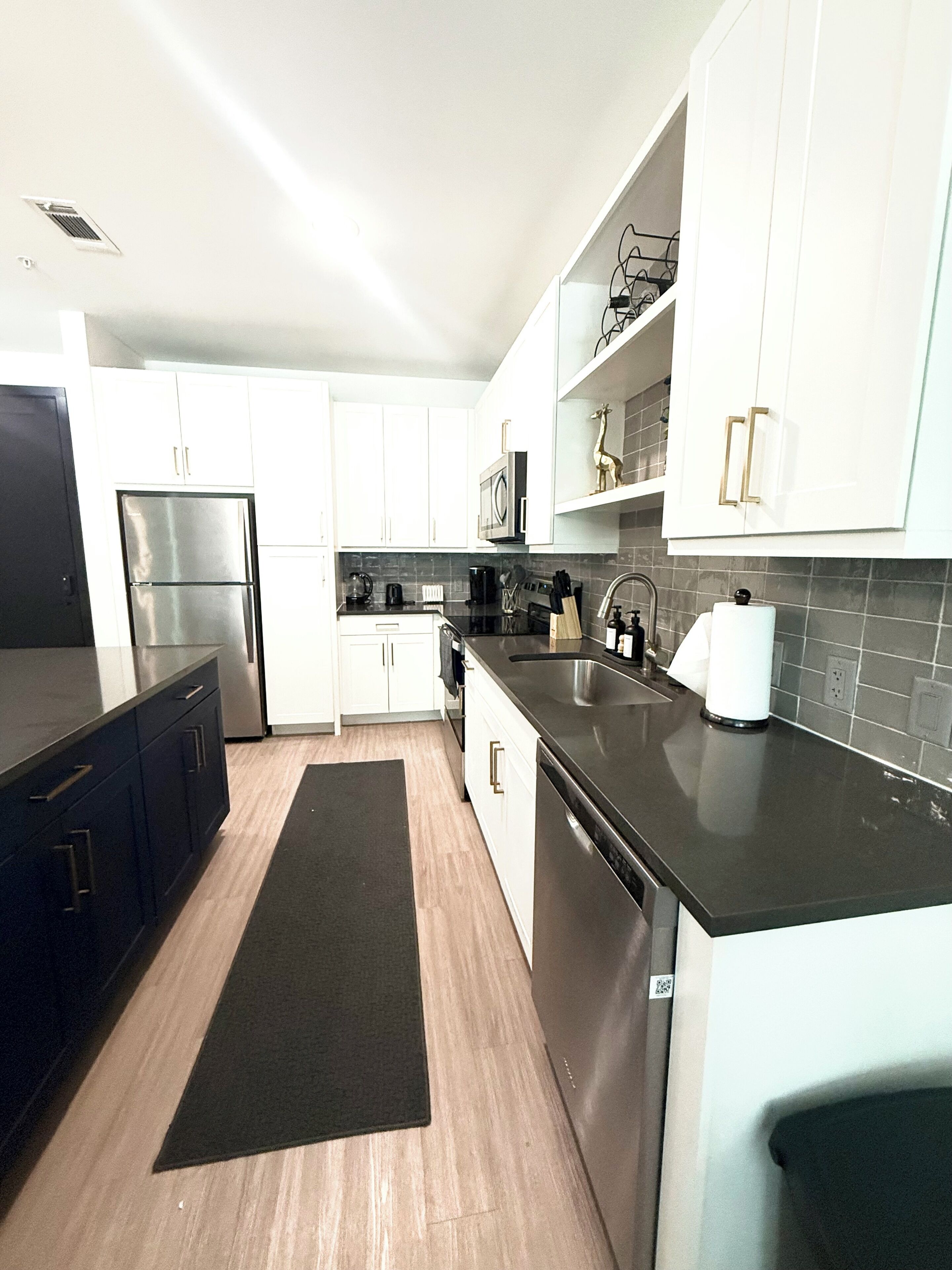A modern kitchen with white cabinets, stainless steel appliances, and a black countertop.