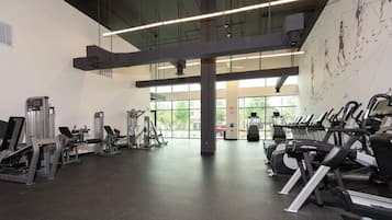 Une salle de sport équipée de divers appareils d’exercice, dotée de grandes fenêtres et offrant une vue sur l’extérieur.