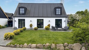 Een twee verdiepingen tellend huis met een schuin dak, grote ramen en een verzorgd gazon.
