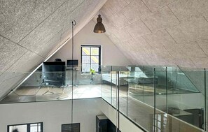 A modern loft with a glass railing, a hanging light fixture, and a view of the outside. - Gorgeous home in Samsø with WiFi (Samsø)