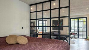 Slaapkamer met een groot bed, een schuifdeur naar een zithoek en uitzicht op de omgeving.