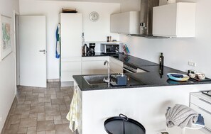 A modern kitchen with white cabinets, a black countertop, a sink, and a microwave. - 2 bedroom nice apartment in Samsø (Samsø)