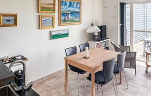 A dining area with a wooden table, black chairs, a TV, and framed artwork on the wall. - 2 bedroom nice apartment in Samsø (Samsø)