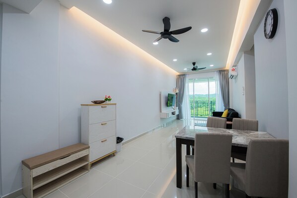 A modern living room with a dining area, a ceiling fan, a TV, and a view of the outdoors.