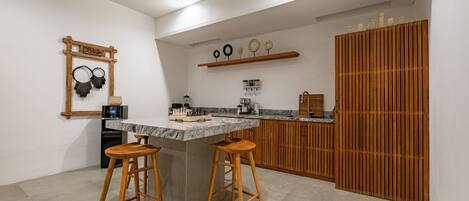 Una cocina con taburetes de madera, ventilador de techo, encimera de mármol y un mueble de madera.