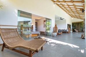 Un vaste espace de vie comprenant un grand fauteuil en osier, une table basse en verre et un ensemble de canapés.