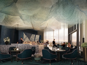 A modern bar area with a high ceiling, seating arrangements, and a city view.