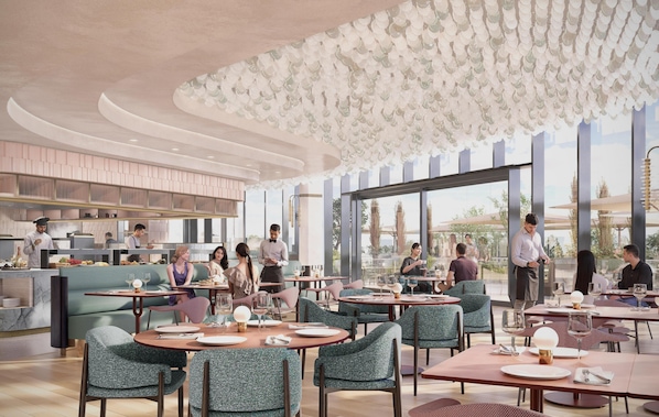 Un interior de restaurante moderno con mesas redondas, sillas tapizadas en verde y vistas al exterior a través de amplios ventanales.
