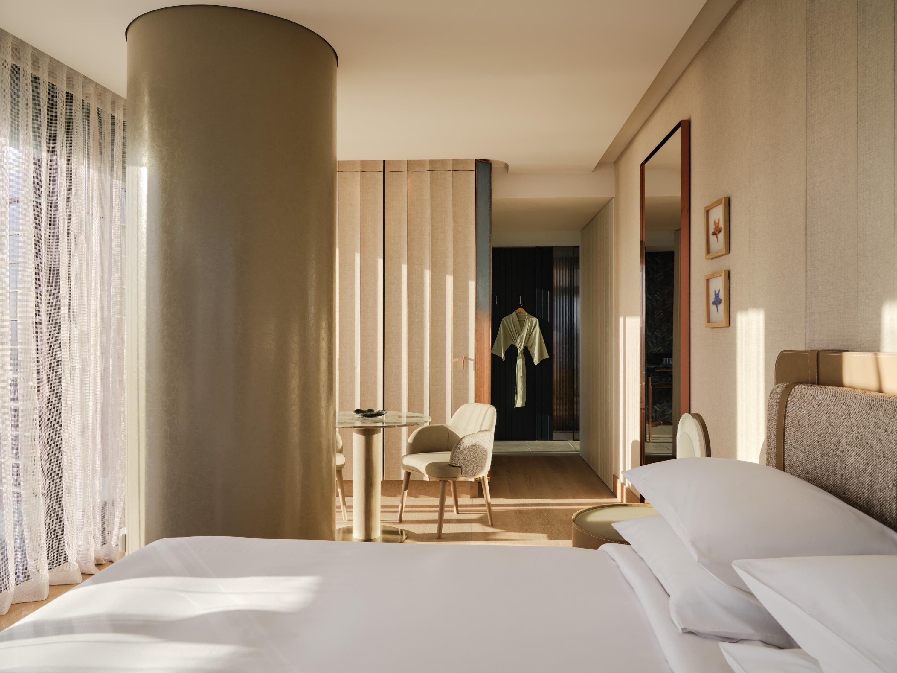 A hotel room with a bed, a desk, a chair, a wardrobe, and a mirror.