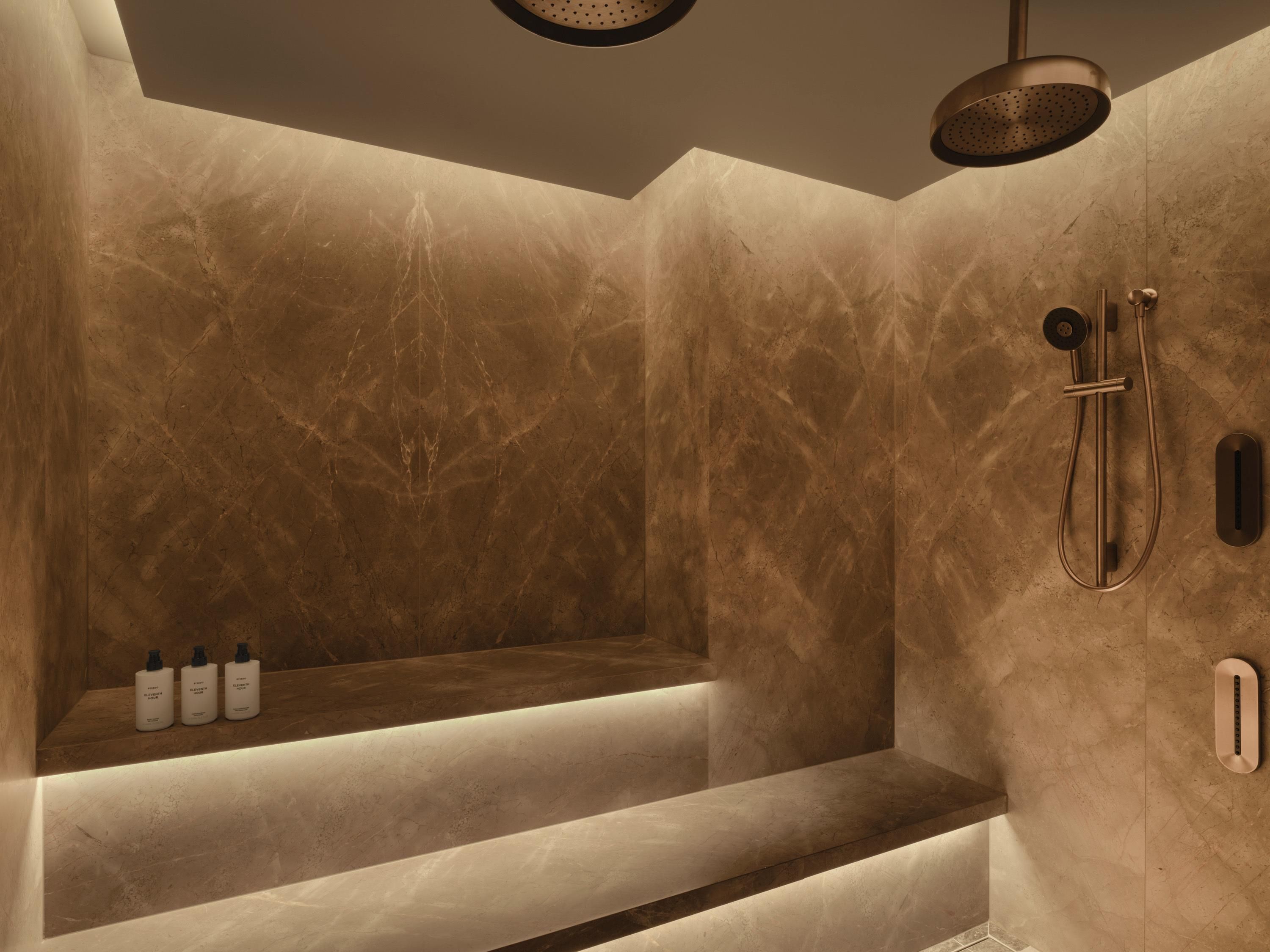 Une salle de bain moderne avec un mur en marbre, un banc intégré et un espace douche.