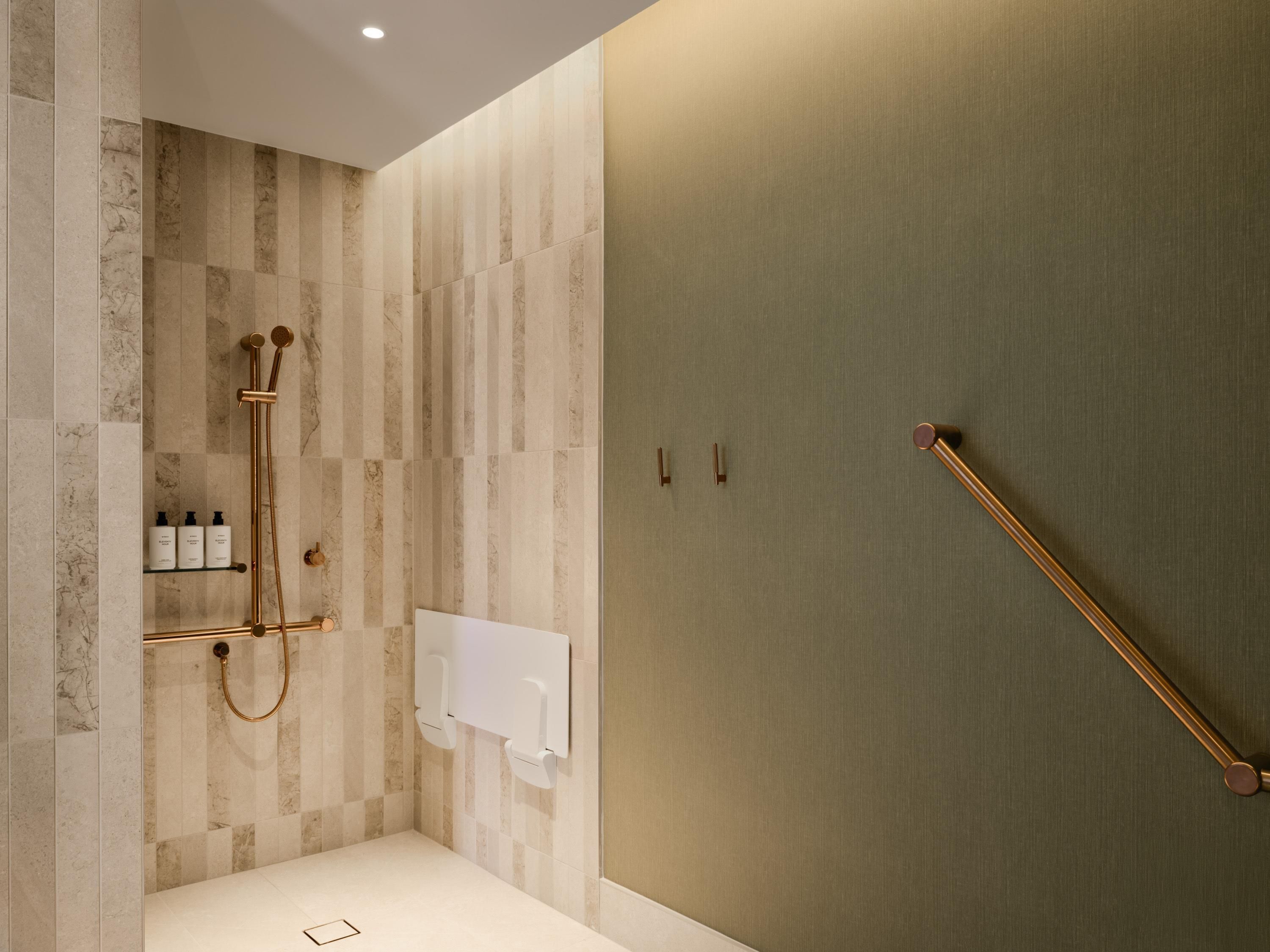A modern bathroom with a shower, a towel rack, and a shelf with toiletries.