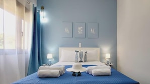 A hotel room with a bed, two bedside lamps, a blue bedspread, a white headboard, and three wall-mounted artworks. - Western Sun near Balos & Falassarna (Trachilos)