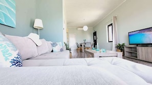 A modern living room with a sofa, a flat-screen TV, a dining area, and a kitchen visible in the background. - Western Sun near Balos & Falassarna (Trachilos)