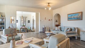 A spacious living room with a sofa, armchairs, a coffee table, and a bookshelf. - Villa Fotis Country House with Sea View, Wi-Fi, and Air Conditioning (Megas Gialos)