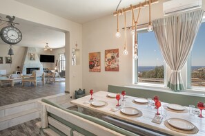 A dining area with a table set for six, a fireplace, and artwork on the walls. - Villa Fotis Country House with Sea View, Wi-Fi, and Air Conditioning (Megas Gialos)