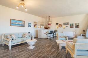 A living room with a sofa, coffee table, and chairs, a kitchen area with a bar, and various wall decorations. - Villa Fotis Country House with Sea View, Wi-Fi, and Air Conditioning (Megas Gialos)