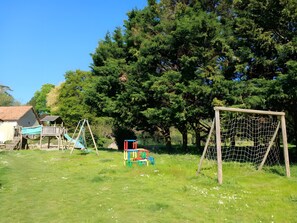 Une aire de jeux avec des balançoires, un toboggan et un but de football.