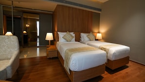 A hotel room with two beds, a chair, and a mirror. - Ramada Encore by Wyndham Kochi Kalamassery (Kanayannur)