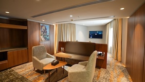 A hotel room with a sofa, two armchairs, a small table, a flat-screen TV, and a painting on the wall. - Ramada Encore by Wyndham Kochi Kalamassery (Kanayannur)
