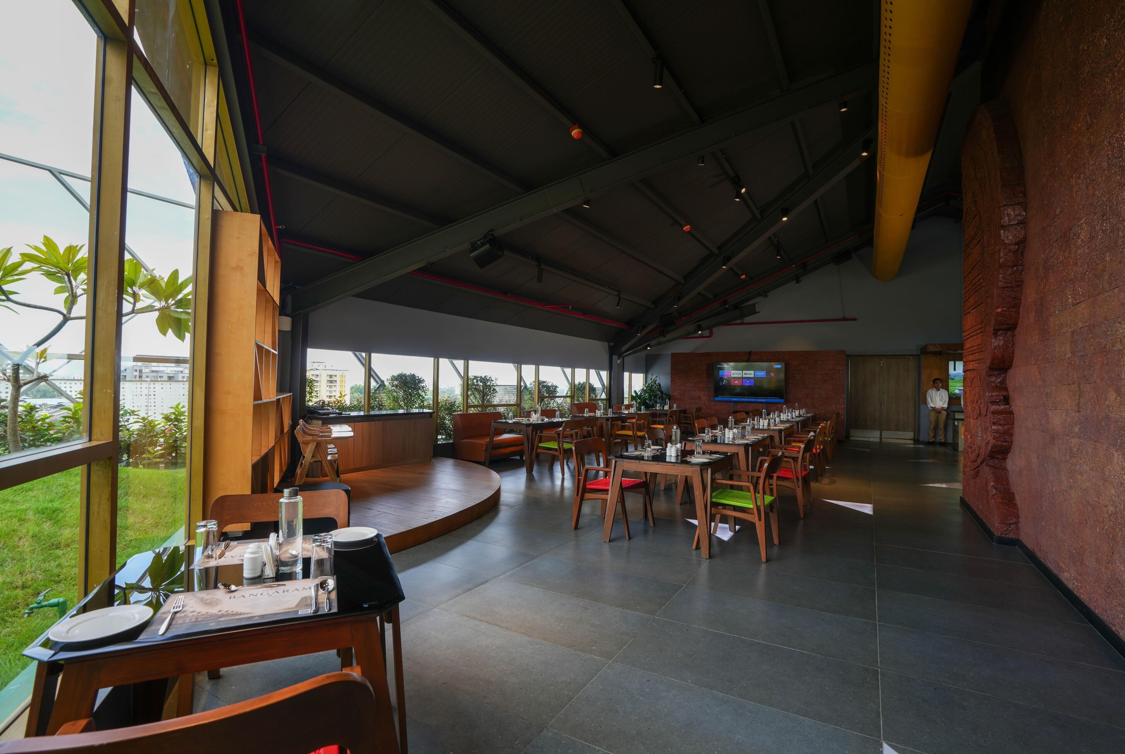 Een restaurant met een hoge plafond, grote ramen en een flatscreen aan de muur.