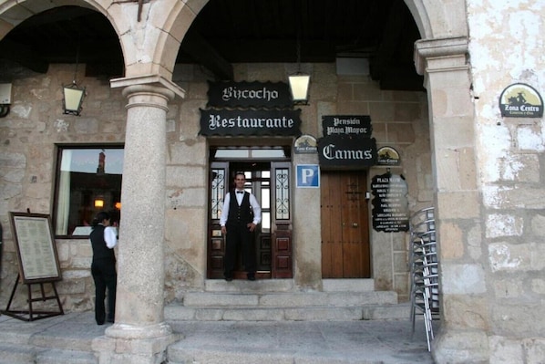 A building with a stone facade, a sign for 'Restaurante', and a 'P' parking sign.