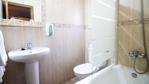 Et badeværelse med vask, toilet og bruser.