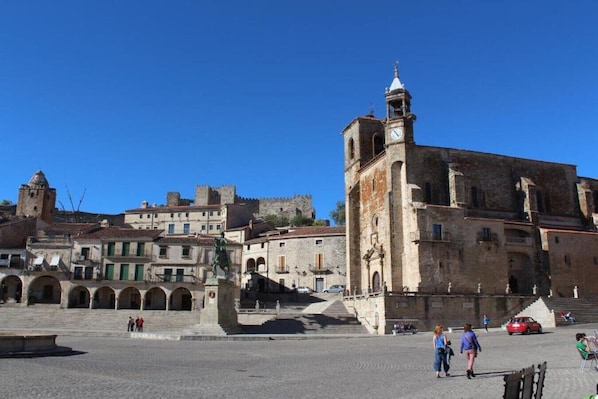 A historic square with a prominent clock tower, stone buildings, and a statue. - Plaza Mayor Trujillo Rooms (Trujillo)