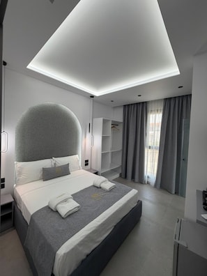 A modern hotel room with a large bed, built-in shelving, and a skylight. - Grand Avelor Hotel (Vlore)