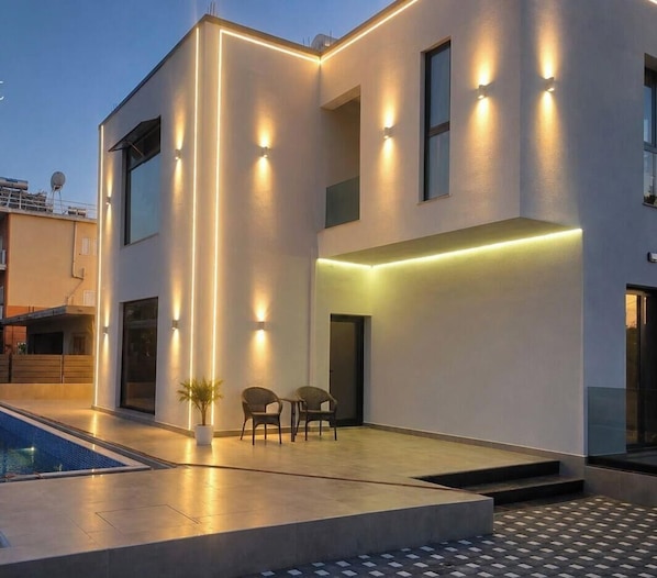 A modern building with a pool, outdoor seating, and illuminated walls. - Grand Avelor Hotel (Vlore)