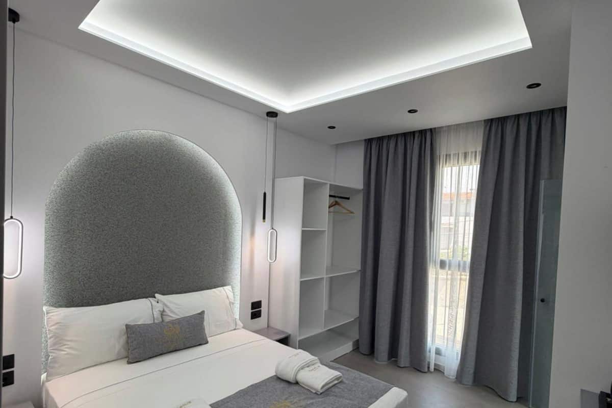 A modern bedroom with a large bed, built-in shelving, and a skylight.