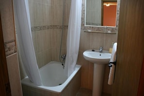 Un baño con bañera, ducha y lavabo.