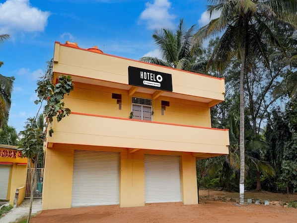 A two-story building with a sign reading 'HOTEL' and a company-serviced logo. There are two closed garage doors at the front.