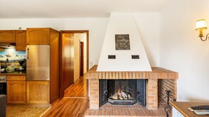 Eine Küche mit Holzausstattung, einem Edelstahlkühlschrank, einem Kamin aus Ziegelsteinen und einer Wandleuchte.