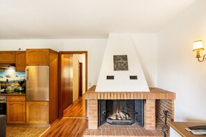 Eine Küche mit Holzausstattung, einem Edelstahlkühlschrank, einem Kamin aus Ziegelsteinen und einer Wandleuchte.