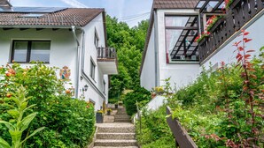 Eine enge Straße mit Häusern an beiden Seiten, eine Treppe, die nach oben führt, und Grünpflanzen.