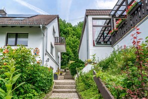 Eine enge Straße mit zweigeschossigen Häusern, einer Steintreppe und üppigem Grün.