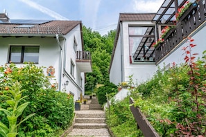 Eine enge Straße mit zweigeschossigen Häusern, einer Steintreppe und üppigem Grün.
