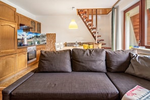 A modern kitchen with wooden cabinets, a built-in oven, and a dining area with a bench and table. - Apartment 'Haus Behrendt' with Mountain View, Balcony and Wi-Fi (Walkenried)