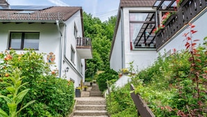 Eine enge Straße mit Häusern an beiden Seiten, eine Treppe, die nach oben führt, und Grünpflanzen.
